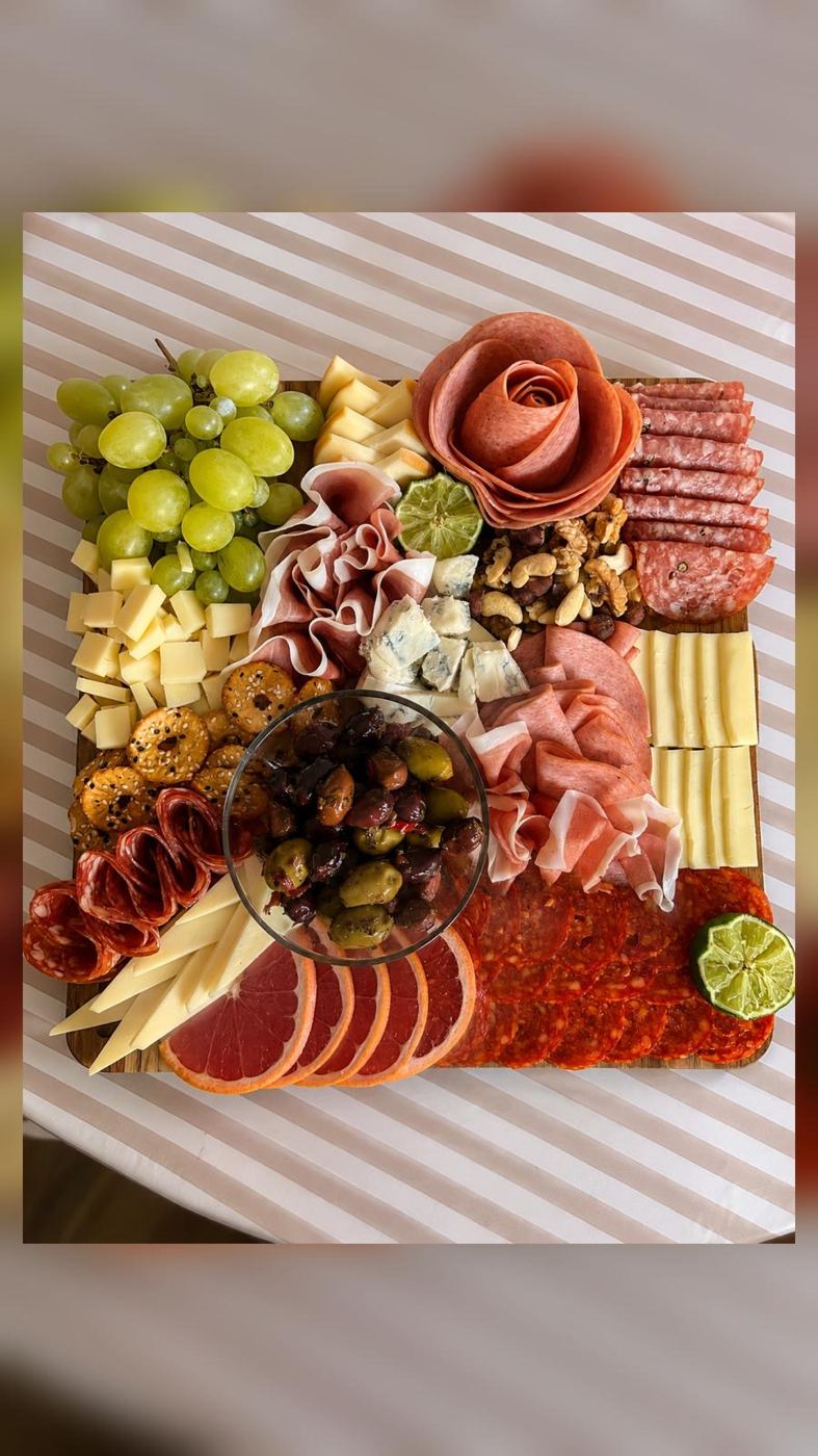 Kvadratna daska sa ružom od salame, sirevima, grožđem i maslinama